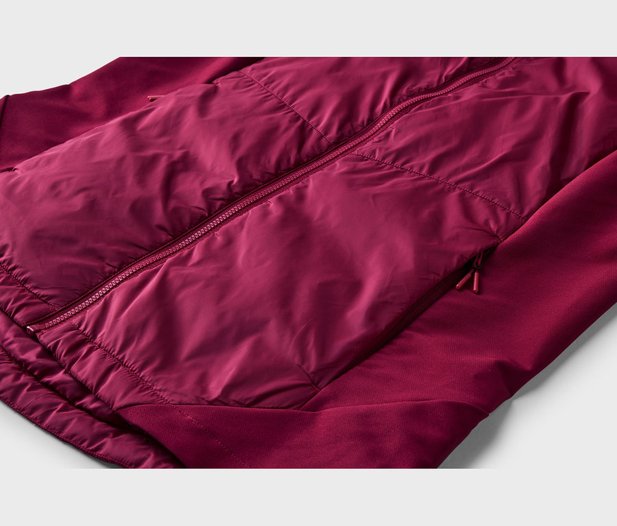 Gros plan d'une veste bordeaux avec un panneau avant matelassé et brillant, et des manches mates. Elle présente une fermeture éclair centrale et une poche latérale zippée.