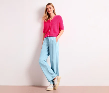 Femme blonde portant un cardigan rose et un jean ample bleu clair Street One « Emee ».