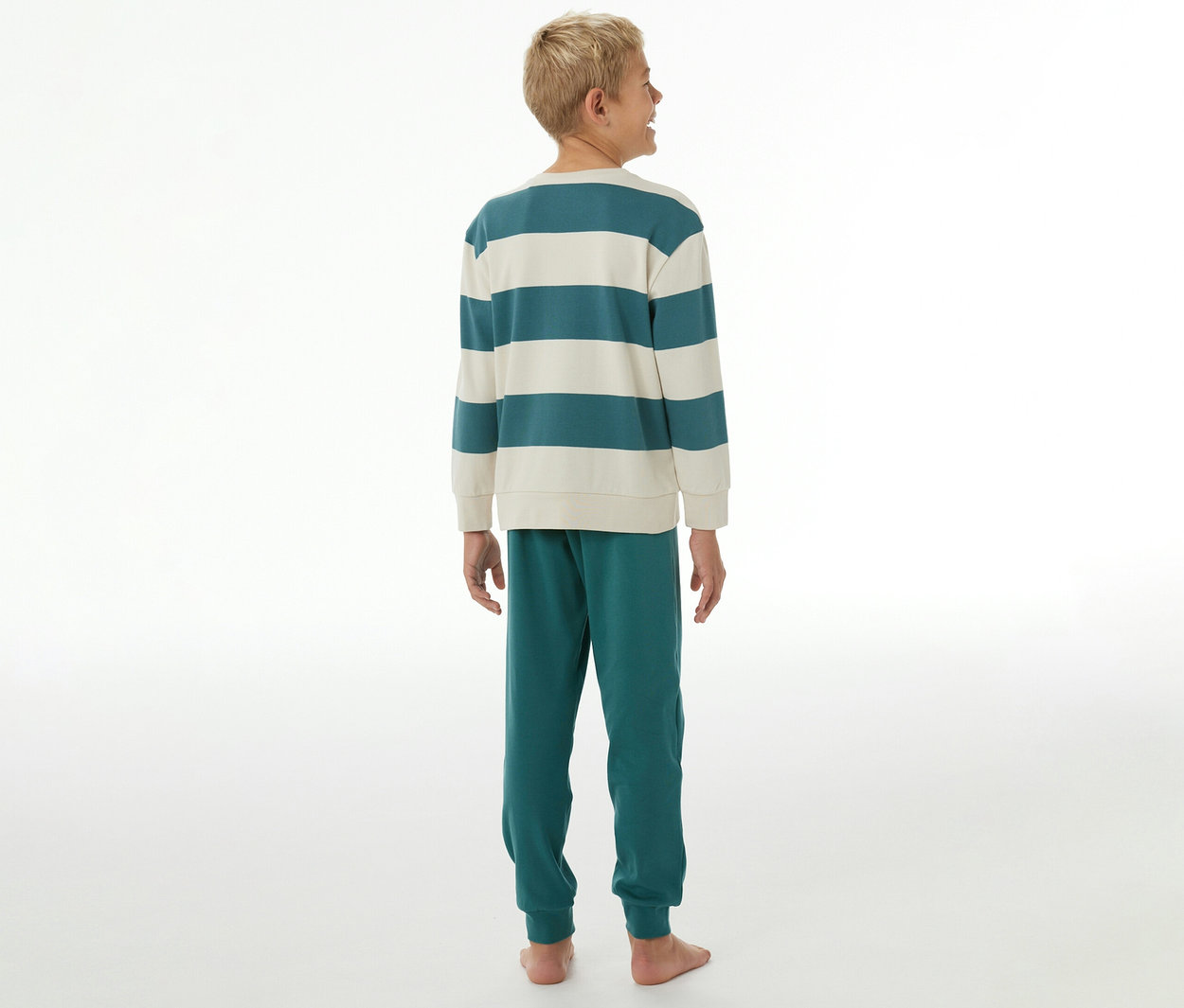 Garçon de dos, portant un pyjama interlock SCHIESSER pour enfant avec un haut rayé sarcelle et crème et un pantalon sarcelle.