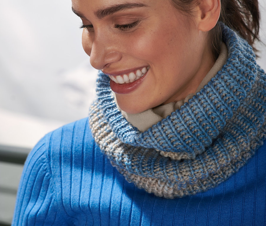 Femme souriante portant une écharpe tube en maille autour du cou.
