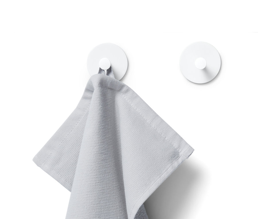 Une serviette grise est suspendue à un crochet blanc, avec un autre crochet blanc visible en arrière-plan.