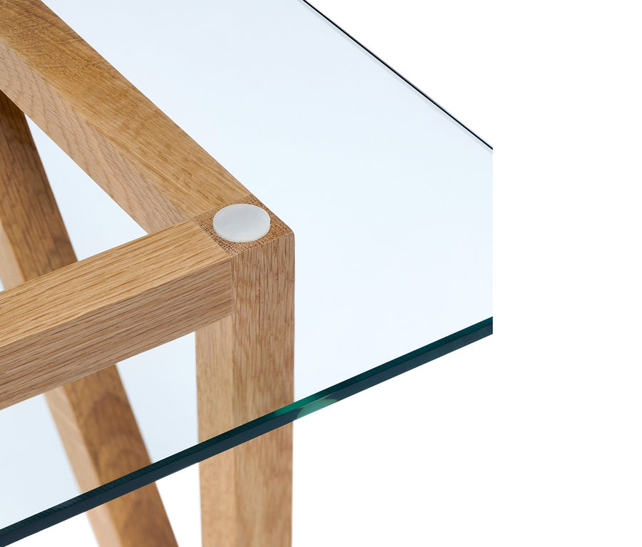 Détail d'un coin de table basse avec cadre en bois et plateau en verre.