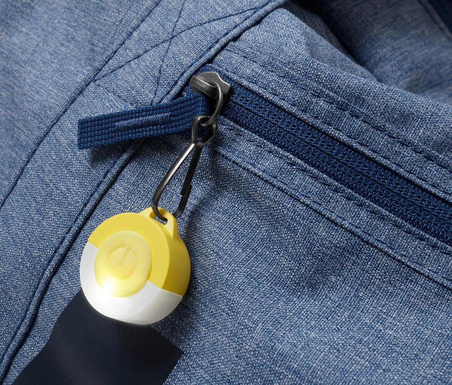 Gros plan sur une veste en tissu bleu avec fermeture éclair et pendentif LED jaune et blanc.