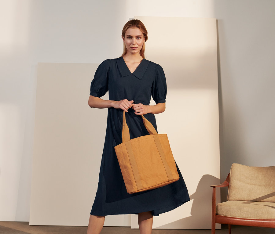 Une femme tenant un cabas porte une robe chemise crêpe.