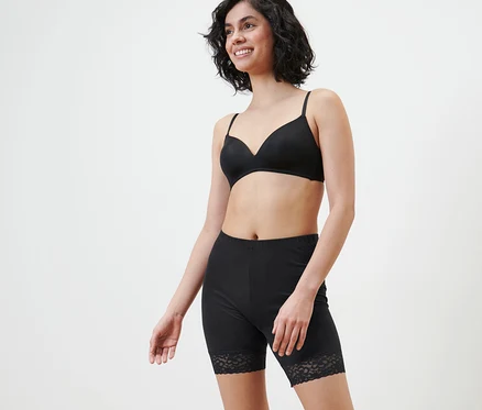 Une femme souriante porte un soutien-gorge noir et un cycliste noir avec bordure en dentelle.