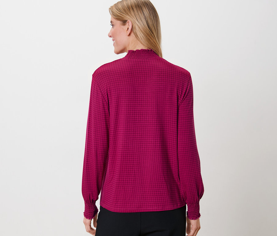 Femme portant une blouse imprimée à col montant.