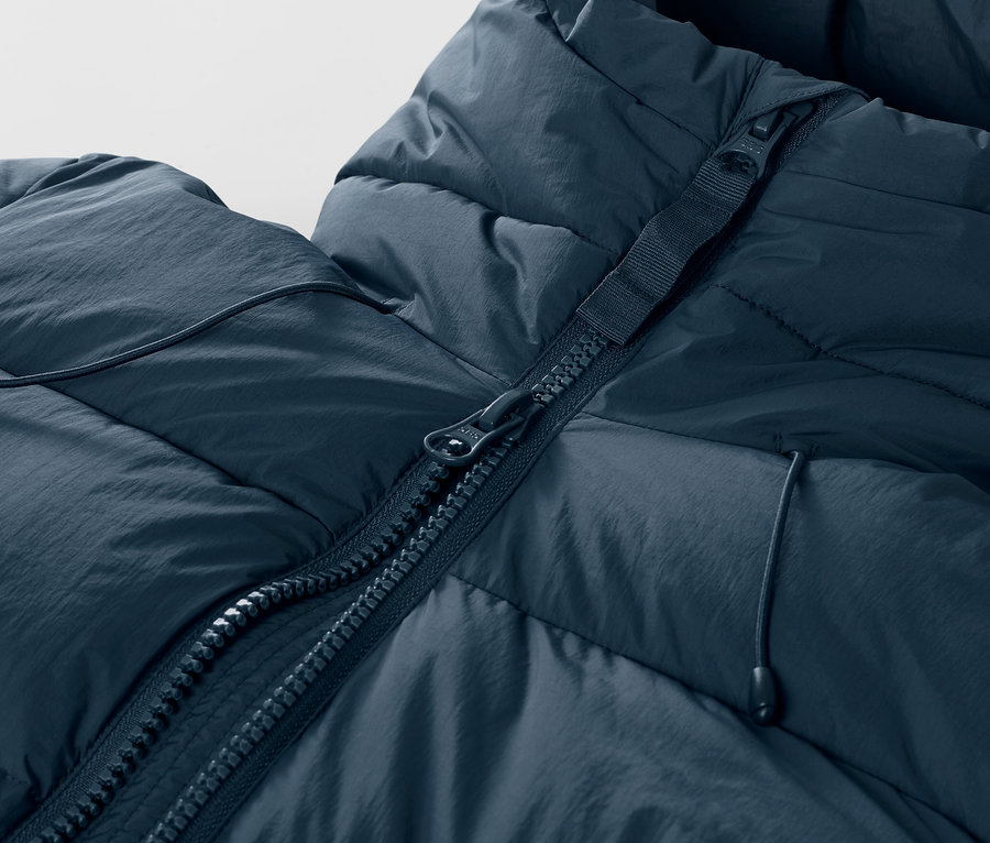 Détail d'une veste de ski matelassée bleu marine avec fermeture éclair.