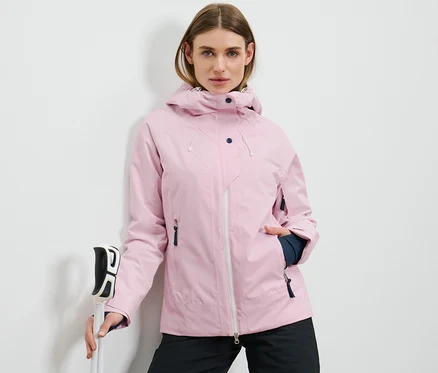 Femme tenant des bâtons de ski et portant une veste de ski rose.