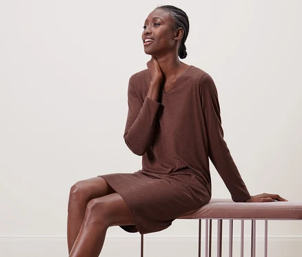 Femme assise sur un banc en chemise de nuit.