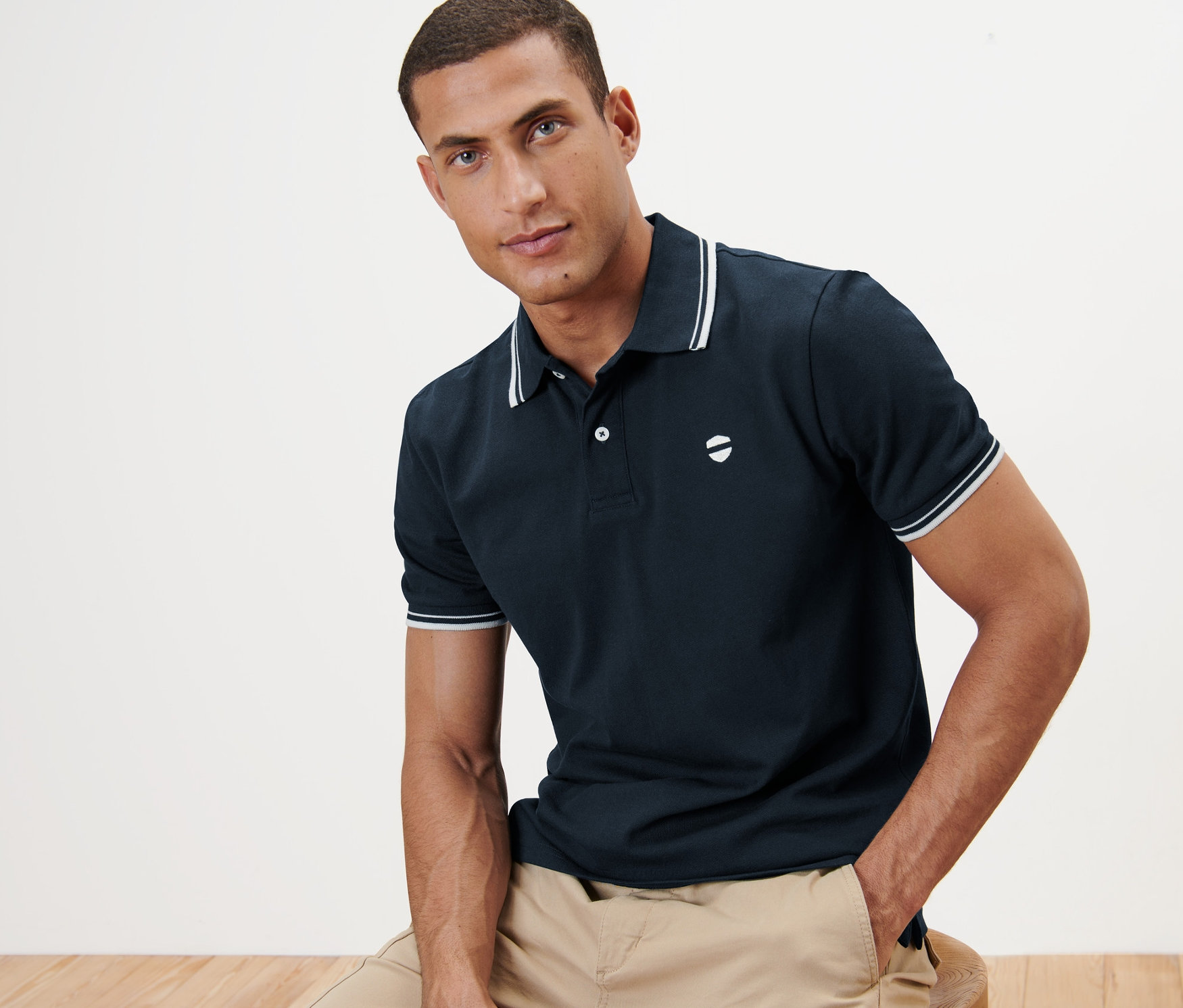 Homme assis portant un polo en piqué bleu marine.