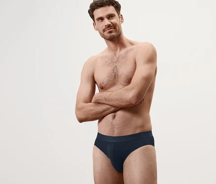 Un homme pose, bras croisés, en portant un des 4 slips.