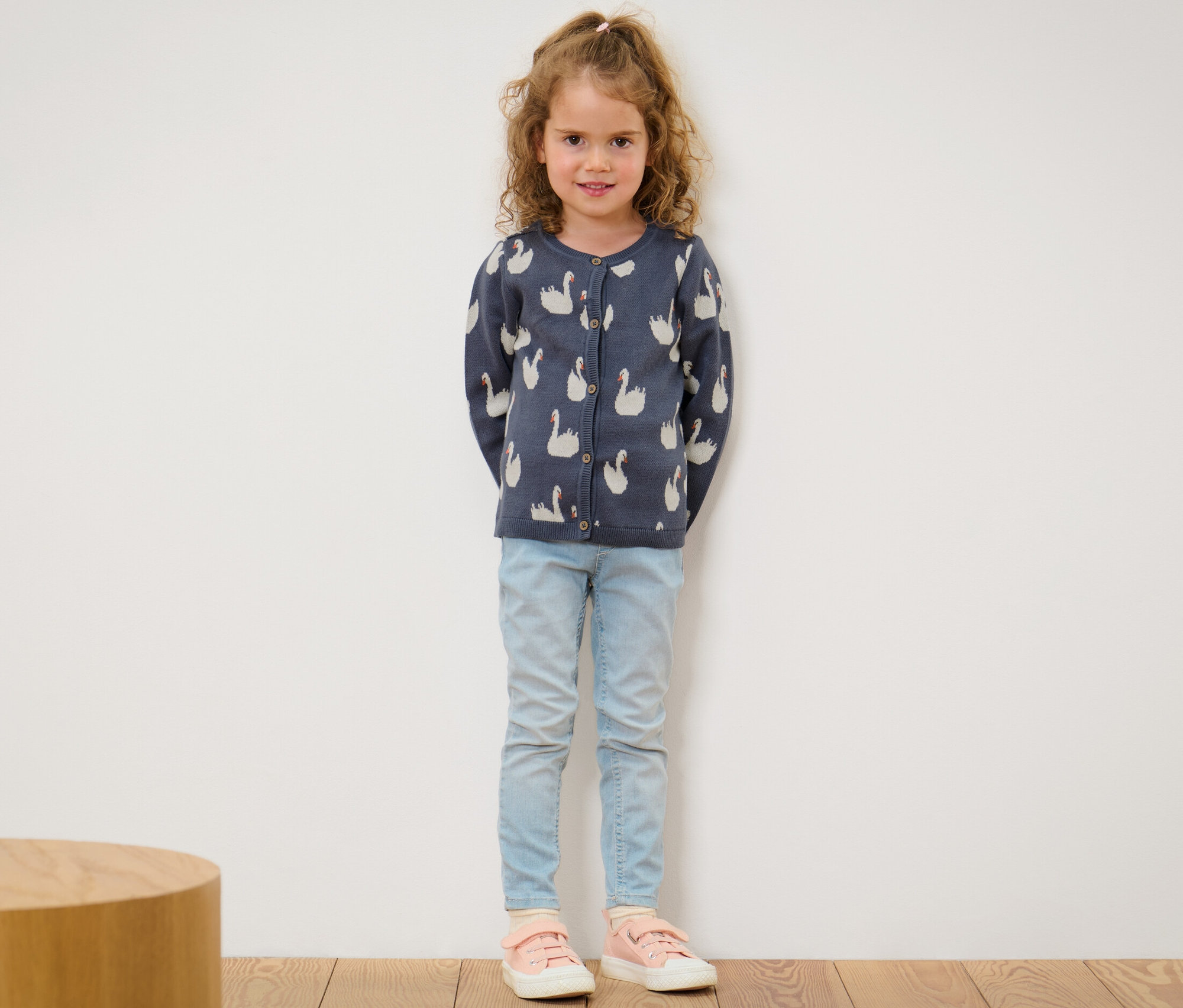 Une fille portant une jaquette en maille pour enfant avec un motif de cygnes.