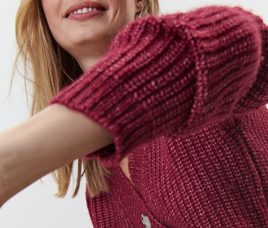 Femme portant un cardigan rouge en grosse maille.