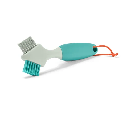 Gros plan d'une brosse à joints, doux/dur, avec un manche bleu-vert et un cordon orange.