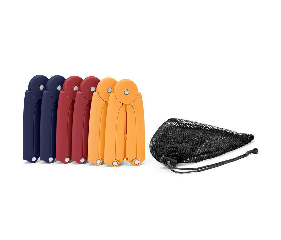 Six cintres de voyage pliables en bleu, rouge et orange à côté d'un sac en filet noir.