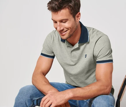 Un homme est assis sur une chaise et porte un polo en piqué gris chiné.