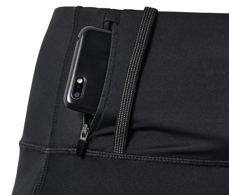Détail d'un legging de course noir haute performance avec une poche zippée dans laquelle est glissé un téléphone portable.