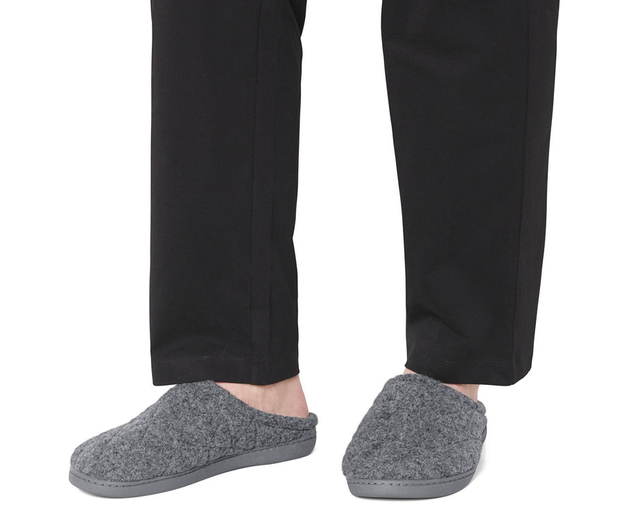 Pieds en pantalon noir et chaussons gris.