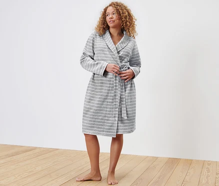 Femme attachant une robe de chambre à rayures grises et blanches.