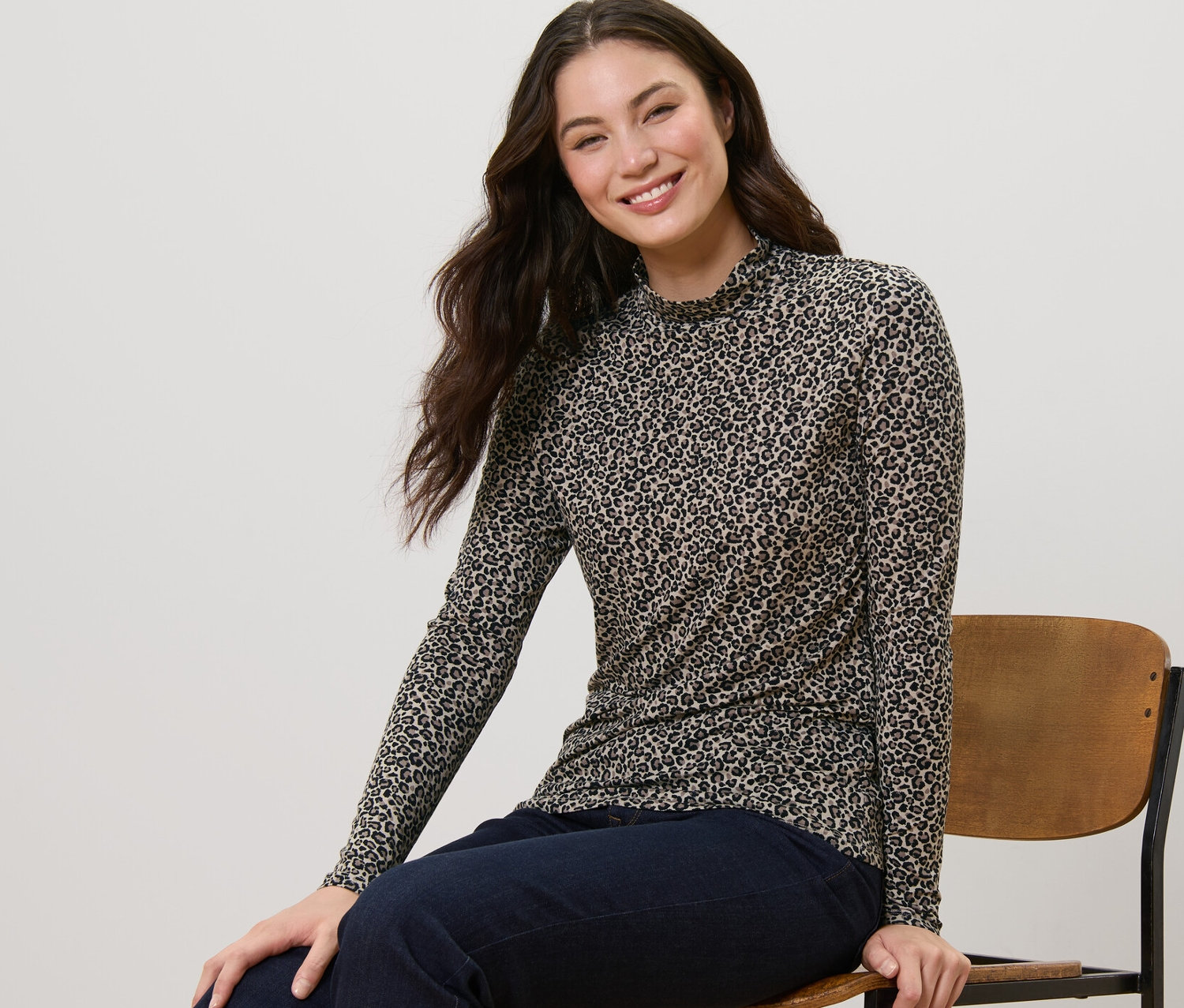 Une femme est assise sur une chaise et porte une blouse imprimée à col montant.