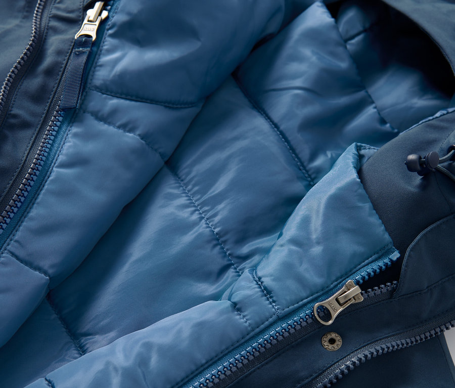 Gros plan d'un manteau technique 3 en 1 avec gilet sans manches ouvert, l'intérieur du gilet est bleu clair.
