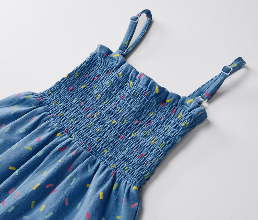 Gros plan sur une combinaison bleue de longueur 7/8 avec des motifs colorés sur un fond blanc.