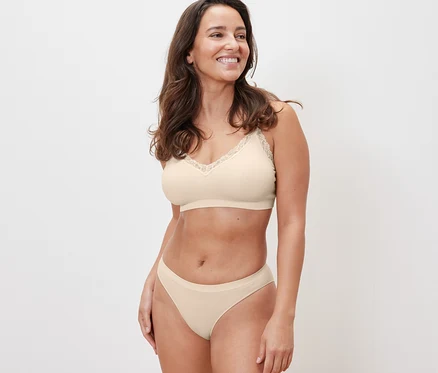 Une femme portant un soutien-gorge sans couture crème avec de la dentelle et 2 slips sans couture, crème.