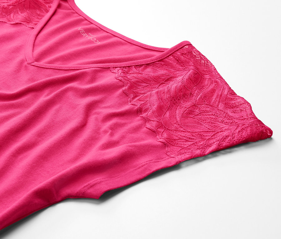 Gros plan d'une chemise de nuit rose avec de la dentelle sur fond blanc.