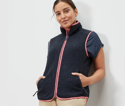 Femme portant un gilet sans manches en peluche teddy avec une bordure rose.
