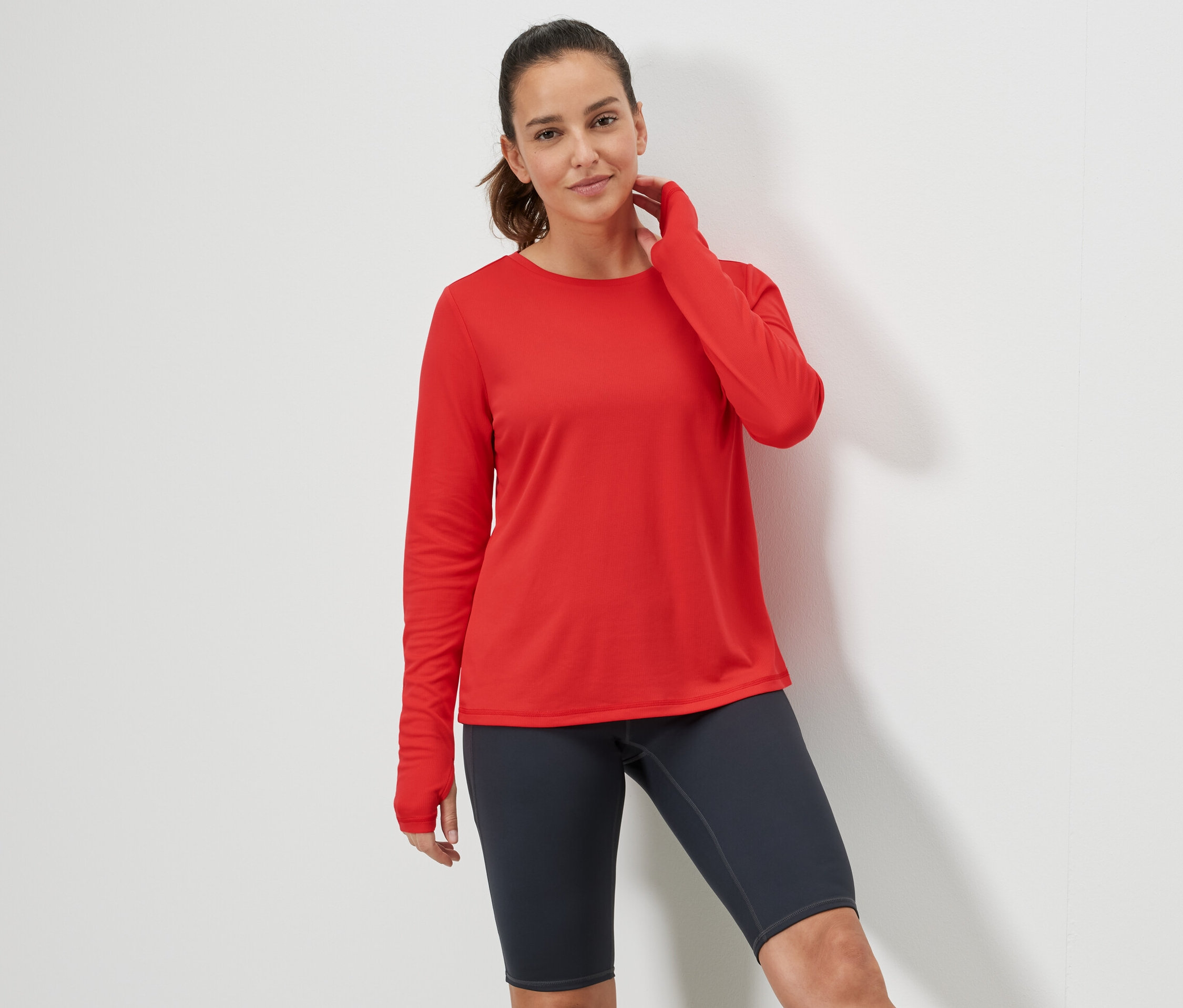 Femme posant dans un t-shirt technique rouge.