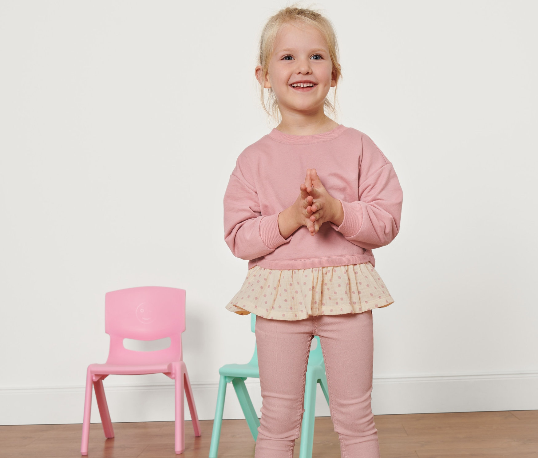 Blonde souriante portant un sweatshirt pour enfant posant en studio.