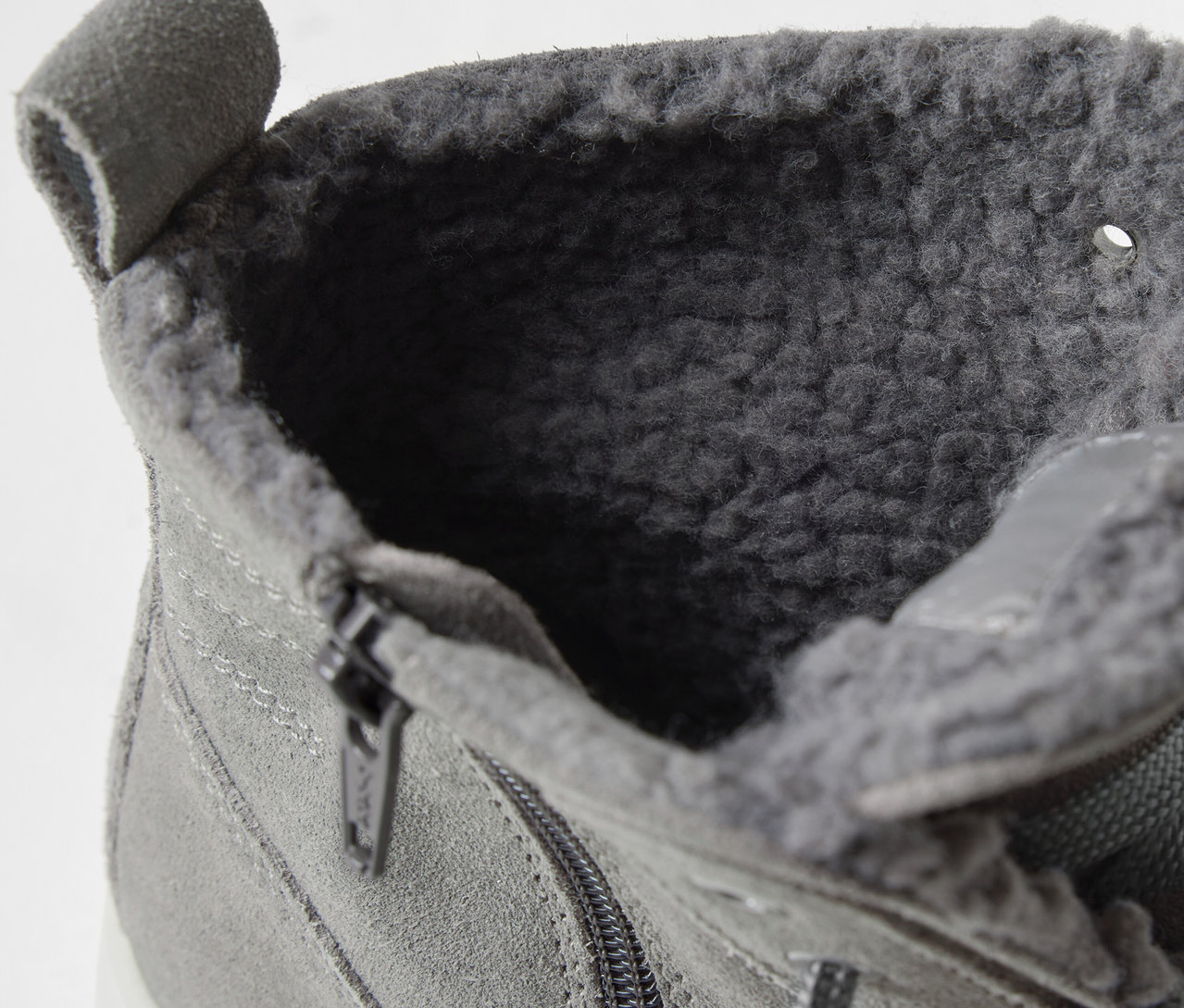 Gros plan d'une bottine grise à lacets avec fourrure intérieure et fermeture éclair.