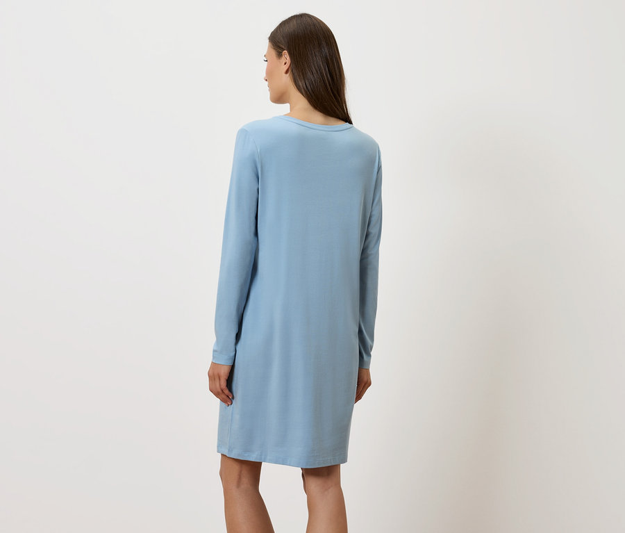 Une femme, dos à la caméra, porte une robe bleue à manches longues.