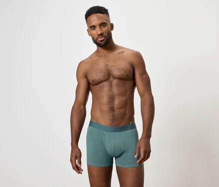 Un homme torse nu pose en boxer vert.