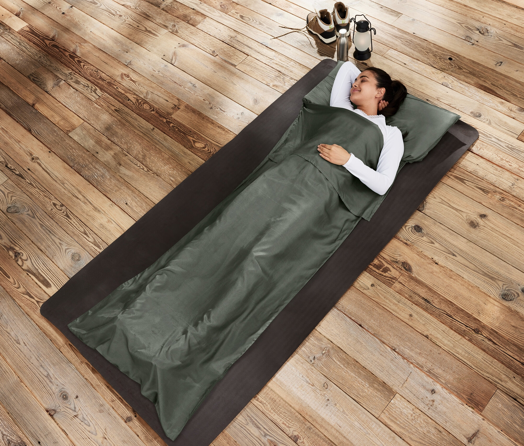 Femme allongée sur un tapis dans un drap de sac de couchage en soie.