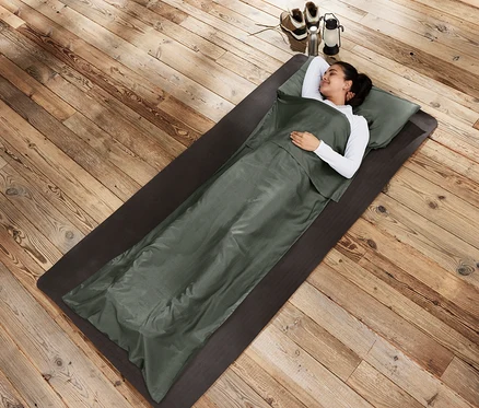 Femme allongée sur un tapis dans un drap de sac de couchage en soie.