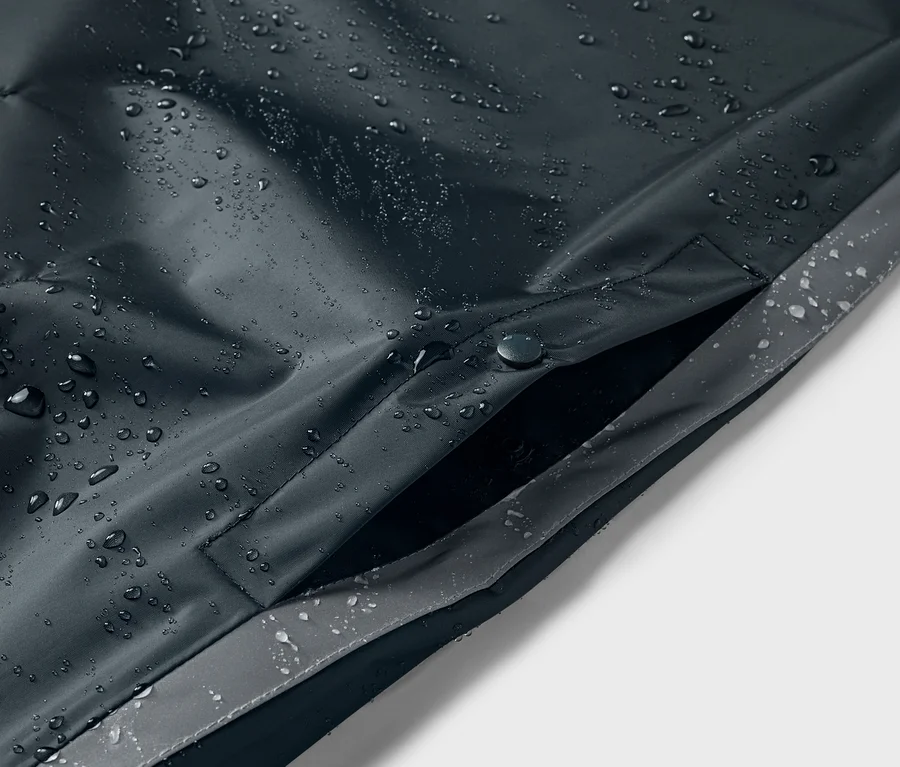 Gros plan sur un poncho de pluie bleu pour enfant avec des gouttes d'eau et une poche.