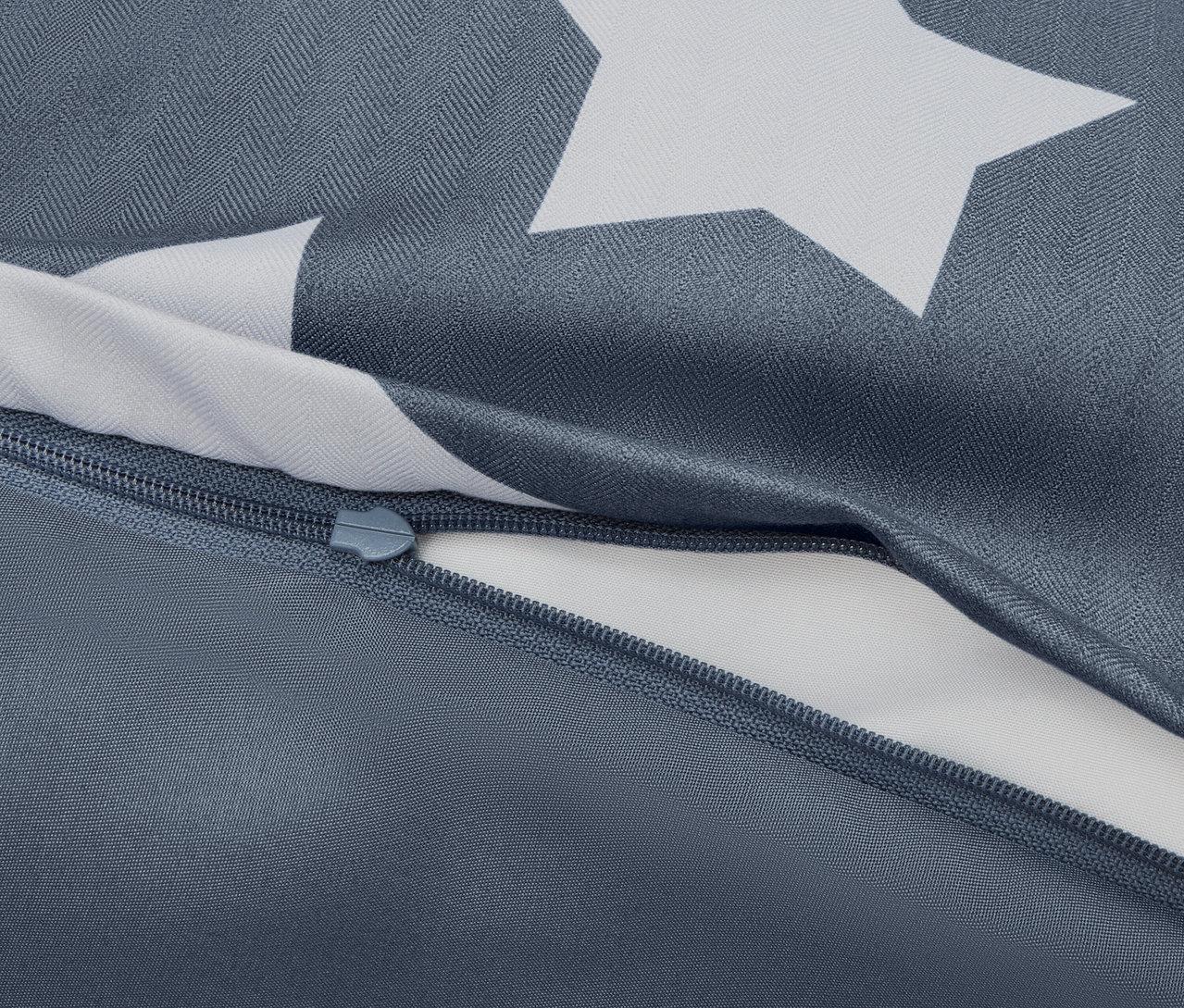 Gros plan d'une housse de couette bleue avec des étoiles blanches et une fermeture éclair partiellement ouverte.