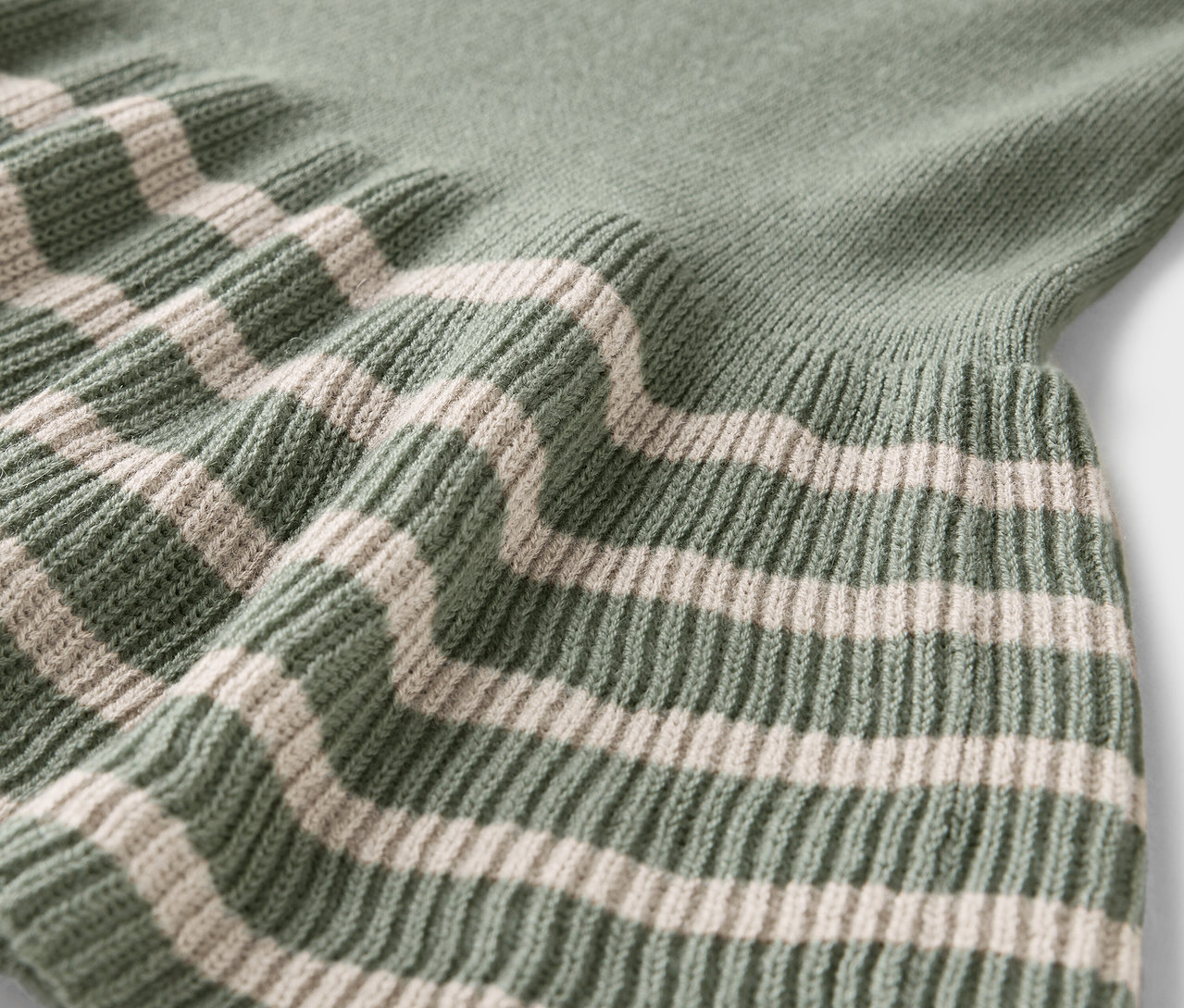 Gros plan sur un pull vert avec des rayures crème.