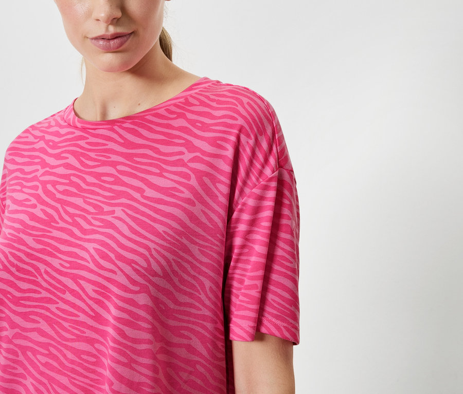 Une femme porte un t-shirt rose à motif animalier.