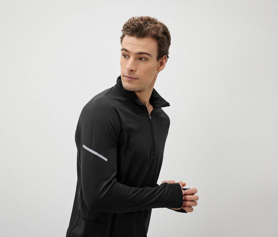 Un homme portant un haut de sport noir regarde par-dessus son épaule.