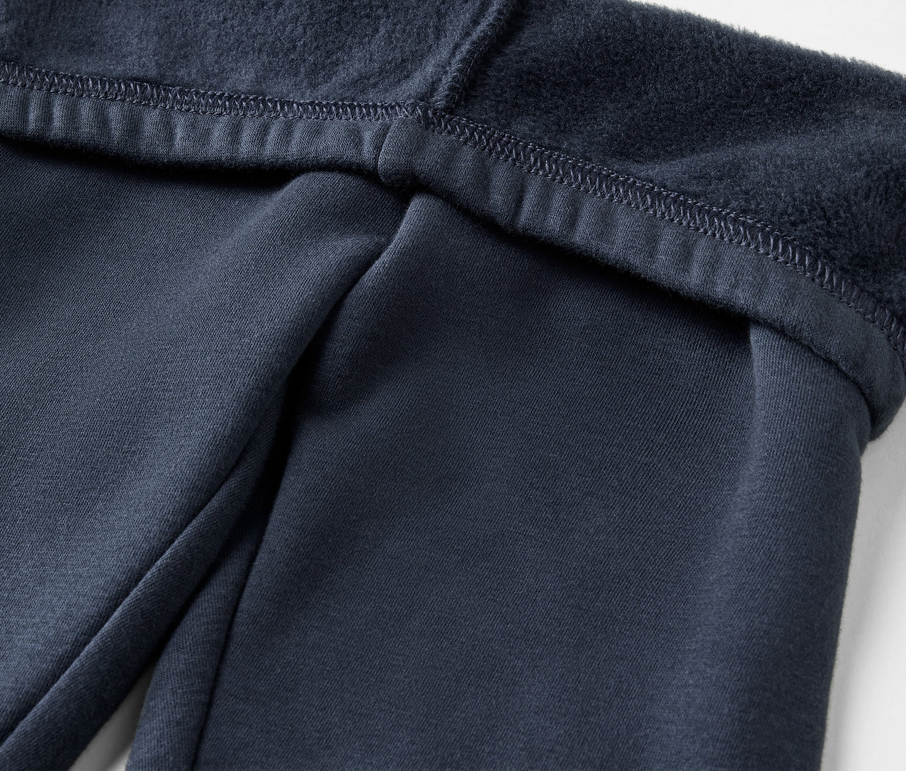 Gros plan d'un pantalon de survêtement bleu marine avec une doublure en polaire.