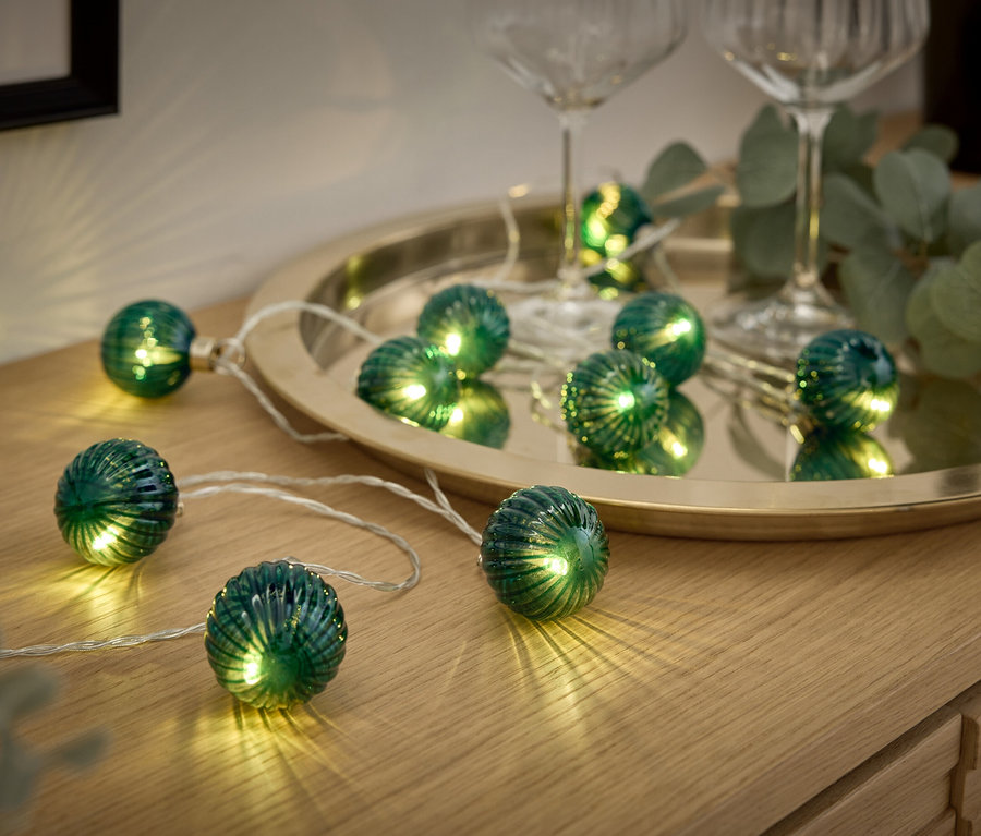 Guirlande lumineuse décorative avec des boules vertes sur une surface en bois.