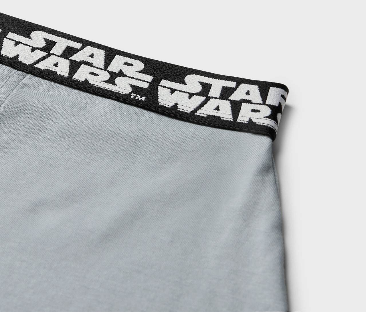 Gros plan sur un boxer gris avec une ceinture noire portant l'inscription STAR WARS en blanc.