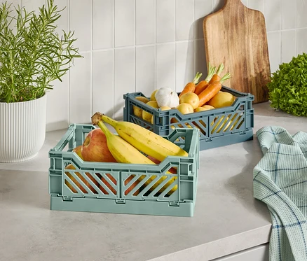 Deux paniers en plastique avec des fruits et légumes sur un comptoir de cuisine.
