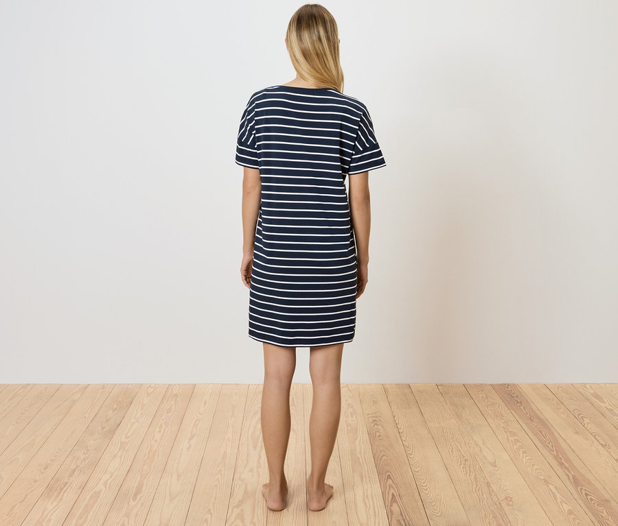 Une femme, vue de dos, porte une robe t-shirt rayée bleu et blanc.