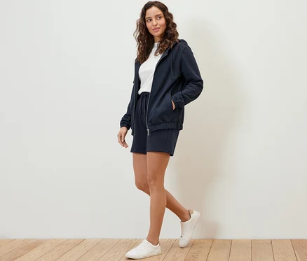 Femme marchant et portant un sweat à capuche et un short bleu foncé.