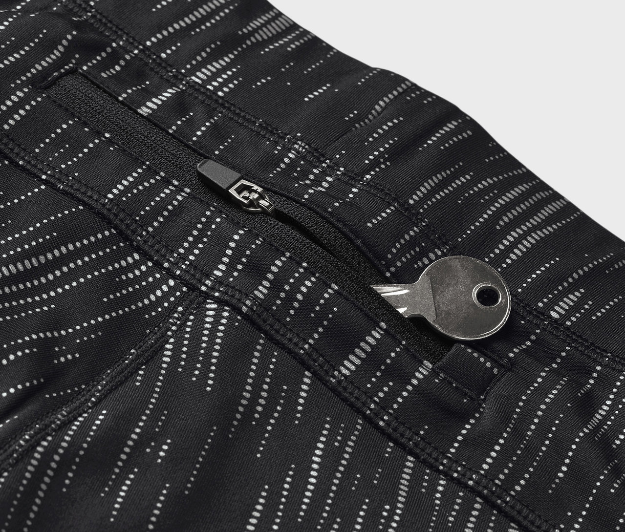Gros plan sur un legging noir à motifs avec une clé dans une poche zippée.
