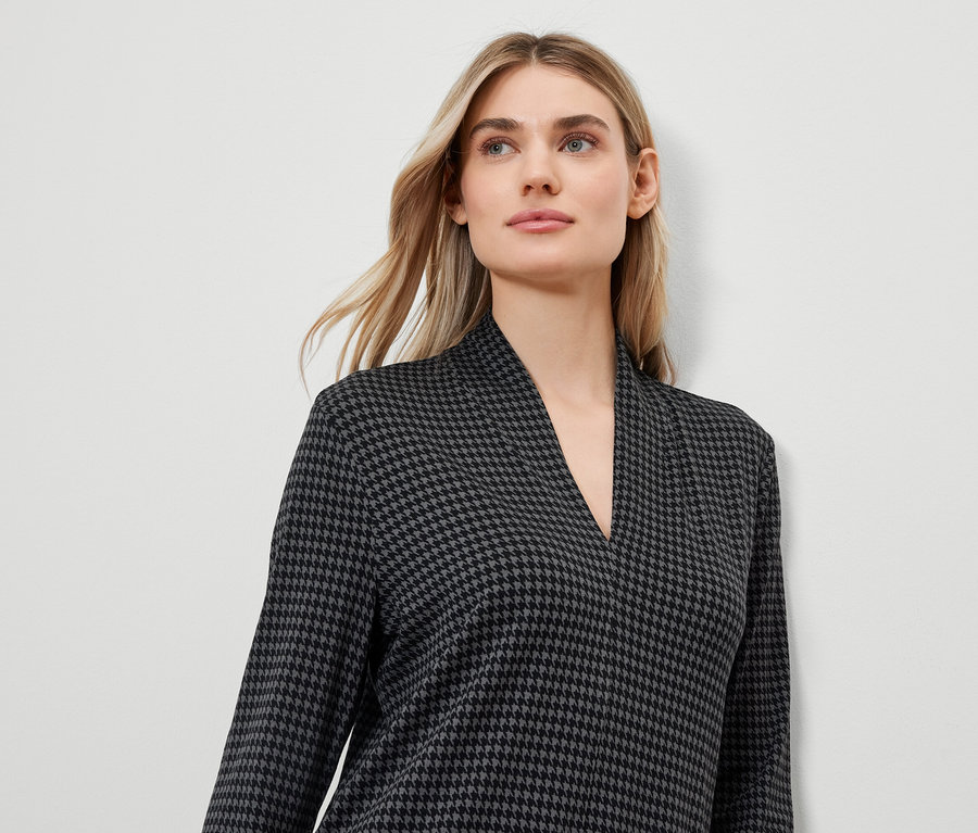 Blonde portant une robe à motif pied-de-poule avec un col en V.