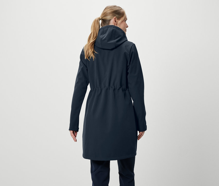 Vue arrière d'une femme blonde aux cheveux attachés en queue de cheval portant un manteau bleu marine et un pantalon.